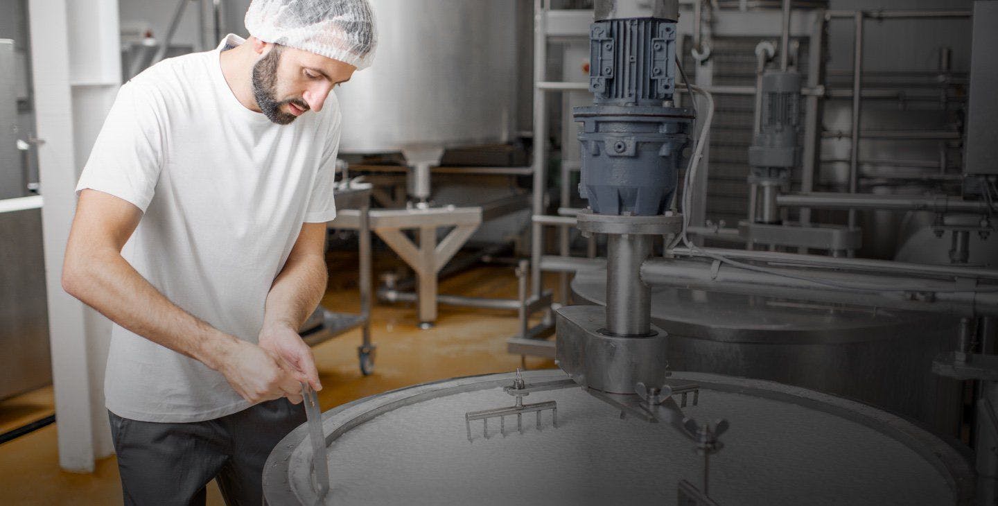 A man in a production facility stirring cream.