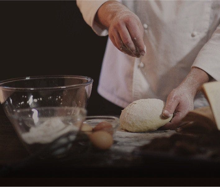 A chef sprinkling flour on some dough.