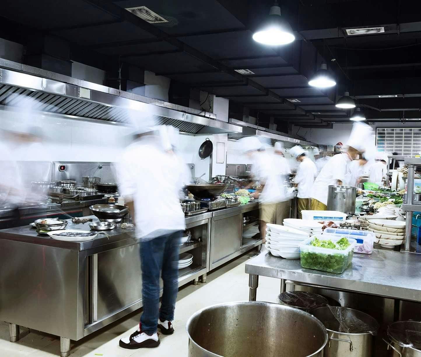 Kitchen staff standing in an industrial kitchen cooking food.