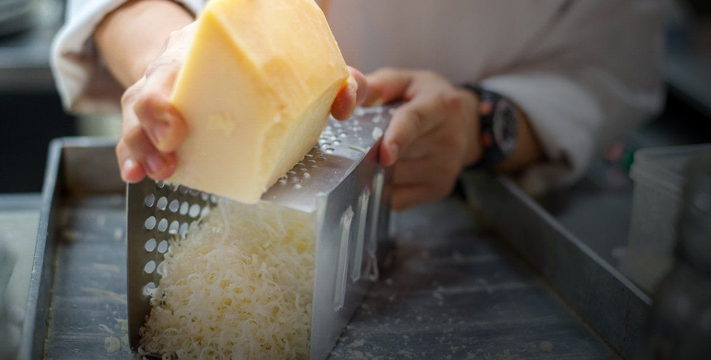 A person shredding cheese on a grater.